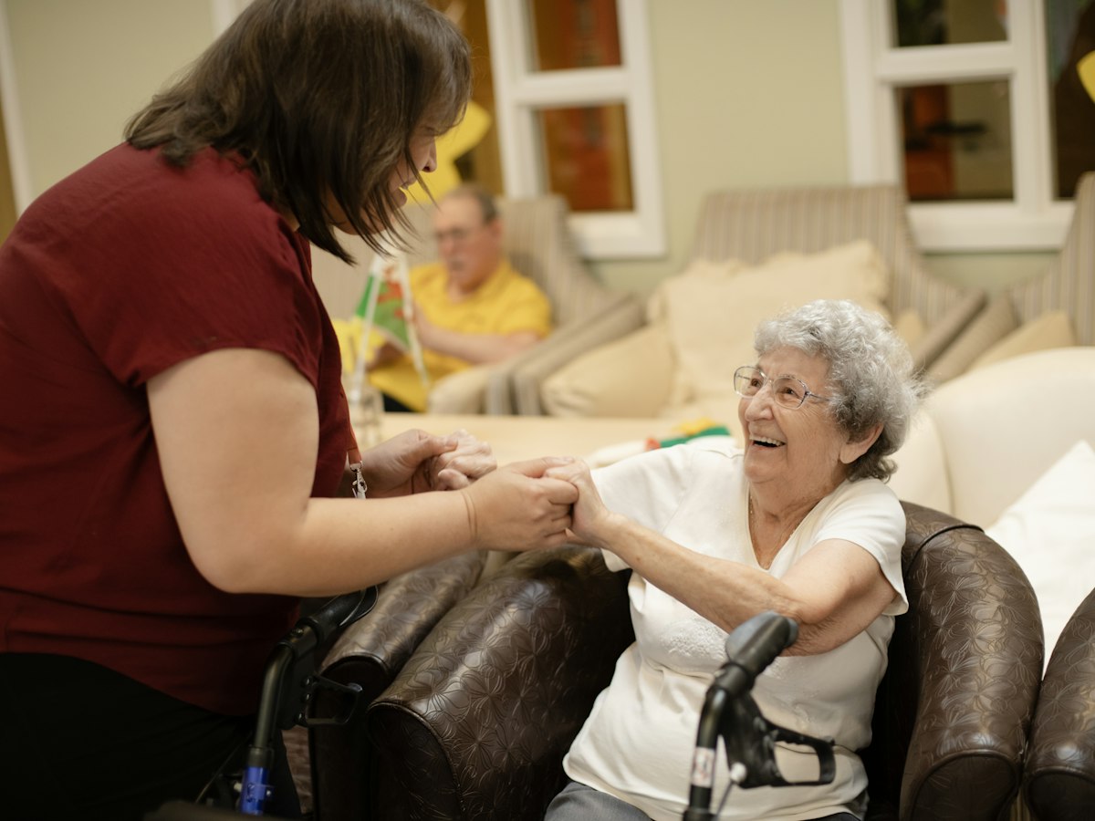 A carer helping an older woman with a walker